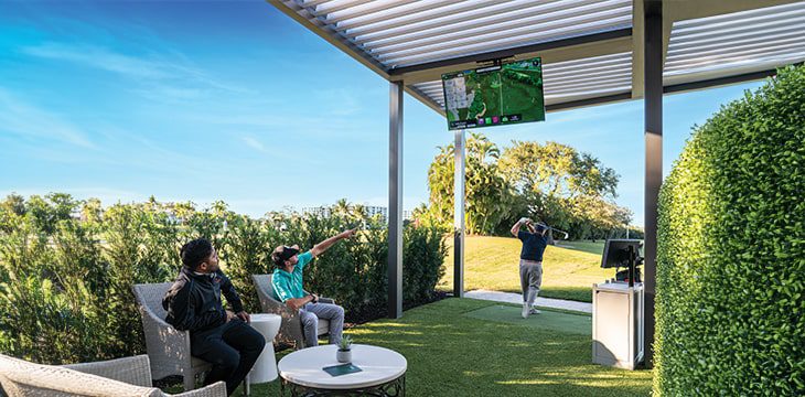 three men at a driving range at Boca West
